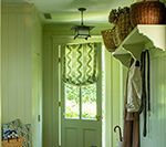 Green entryway with door, window, shelves, baskets, and coats.