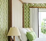 Bedroom with light green patterned accents on the bed frame, walls, and pillows. A lamp sits by the bed.