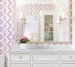 White bathroom vanity with marble top, large mirror reflecting a built-in cabinet, light purple patterned wallpaper.
