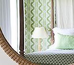 Bedroom interior with a bed, patterned green curtains, and a lamp.