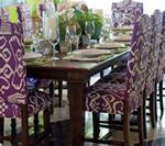 Dining table set with patterned purple chairs, place settings, and centerpiece.