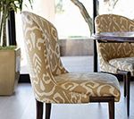 Upholstered dining chair with tan and white patterned fabric, dark wood legs.