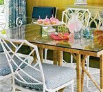 Dining room with bamboo table, white geometric chairs, and colorful decor.