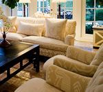 Cream-colored sofa and armchairs in a well-lit living room, with a dark wooden coffee table.