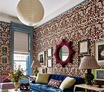 Living room with patterned wallpaper, blue velvet sofa, and decorative items.