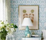 Bedroom scene with floral wallpaper, a lamp, and framed artwork.