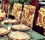 Table setting with patterned chairs; green tablecloth, plates, silverware, and decorative centerpieces.