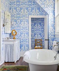 Bathroom with blue and white patterned wallpaper, a white bathtub, and a doorway.