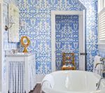 Blue and white patterned wallpaper in bathroom with a white tub and vanity.