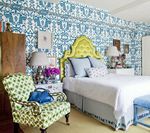 Bedroom with patterned blue wallpaper, lime green headboard, and patterned green chair.
