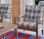 Two armchairs with patterned cushions and striped seats, in a room with a striped rug.