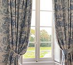 Window with blue and white patterned curtains, overlooking a garden.