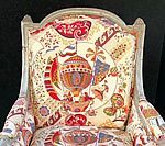 Upholstered chair with a cream-colored frame and patterned fabric featuring hot air balloons in red, orange, and blue.