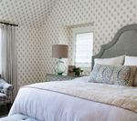 Bedroom with patterned wallpaper, grey bed frame, and neutral bedding.