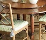 Wooden dining table with chairs; chairs have patterned cushions and bamboo-style backs.