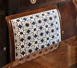 Close-up of a chair back with a blue and white floral patterned cushion and brown wooden frame.