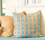Two decorative pillows, one tan and one blue striped, on a blue surface.