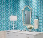 Bathroom with turquoise patterned wallpaper, white vanity, mirror, and towel rack.