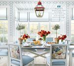 Dining room with a table set for a meal, floral arrangements, and light blue chairs.