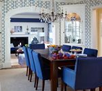 Dining room with blue chairs, dark wood table, and patterned wallpaper.