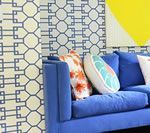 Blue sofa with patterned pillows against patterned wall and a yellow triangle.