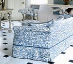 Blue and white patterned sofa and chairs in a room with a black and white tiled floor and white furniture.