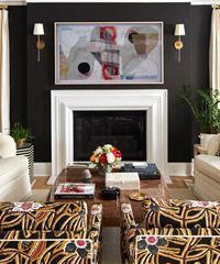 Living room with dark gray wall, fireplace, abstract art, patterned chairs, and gold accents.