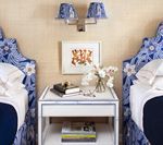 Twin beds with blue floral headboards and a shared nightstand, decorated with artwork and flowers.