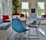 Dining room with blue chairs, a white table, and built-in bench seating with colorful pillows.