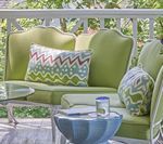 Outdoor seating area with lime green cushions and decorative pillows. A blue side table is in front.