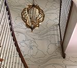 Stairwell with floral wallpaper and gold chandelier hanging from the ceiling.