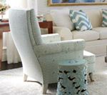 Light blue patterned armchair with matching footstool in a living room; light carpet.