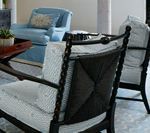 Two dark wood armchairs with light patterned cushions; a blue chair in the background.