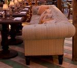 Cream-colored upholstered sofa in a restaurant setting, next to a table and chairs.