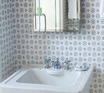 Bathroom with a white sink, patterned wallpaper, a mirror, and chrome fixtures.
