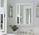 Bathroom with patterned wallpaper, large mirror, white cabinets, and a sink with silver fixtures.
