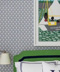 Green headboard with blue trim and patterned wallpaper, artwork of sailboats.