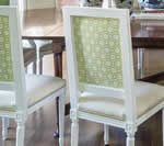 White dining chairs with patterned green backs, cream seats, and wooden legs.