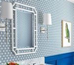 White framed mirror and sconces on blue patterned wall with framed bird art.
