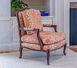 Armchair with orange paisley fabric, dark wood frame, in front of a white built-in shelf.