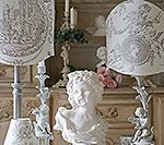 Decorative lamps and bust in a room with a detailed wall.