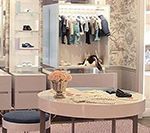 Walk-in closet with hanging clothes, a round table with accessories, and shelves with shoes.