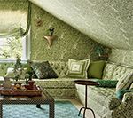 Green floral patterned room with built-in seating, patterned walls, and a small table.