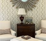 Two white chairs face a dark wood dresser with a lamp and mirror on the wall, and an ottoman in the foreground.