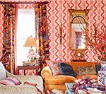 Living room with orange and patterned wallpaper, curtains, sofa, and a mirror.