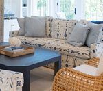 Living room with patterned sofa, blue pillows, dark coffee table, and wicker chair.