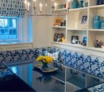 Dining room with built-in blue patterned banquette seating, black table, and white shelves with blue decor.