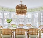 Dining room with a white table, rattan chairs, and a layered woven chandelier.