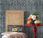 A chair with a zebra print clutch and plaid blanket, next to a red side table with flowers.