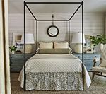 Bedroom with canopy bed, blue nightstands, and mirror on the wall.